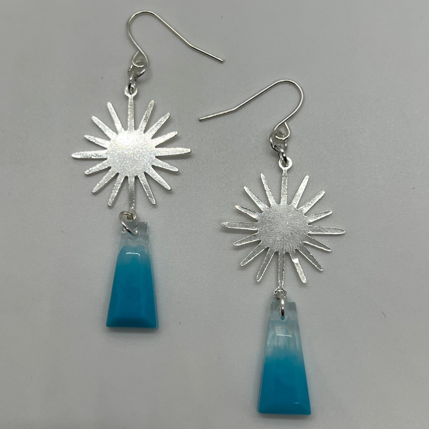 Silver sun charm with blue shapes