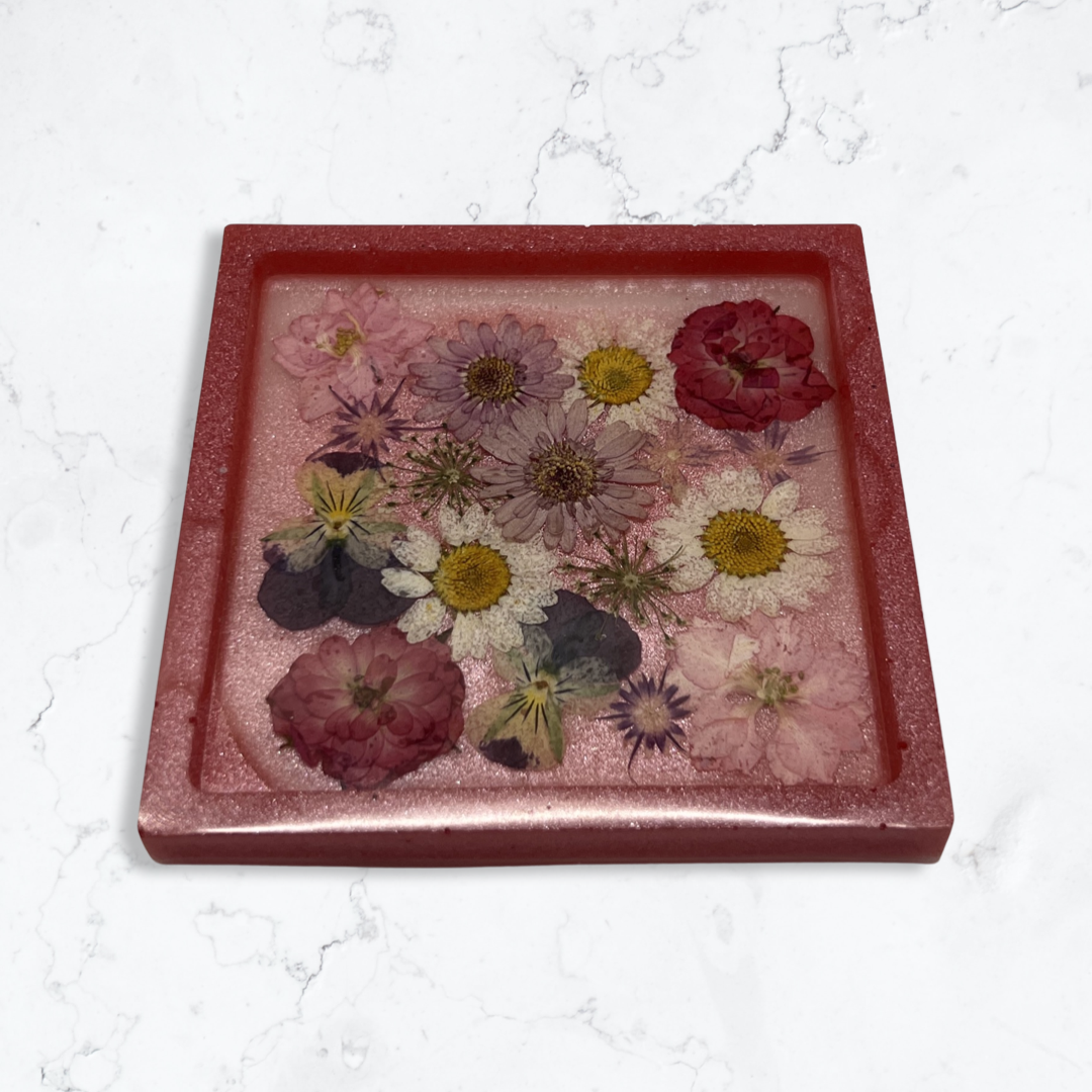 Pink square coaster filled with multicolored flowers