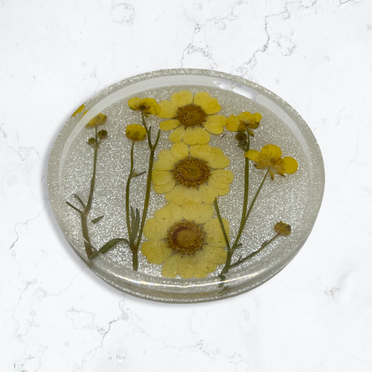 Silver circle coaster filled with sunny yellow flowers